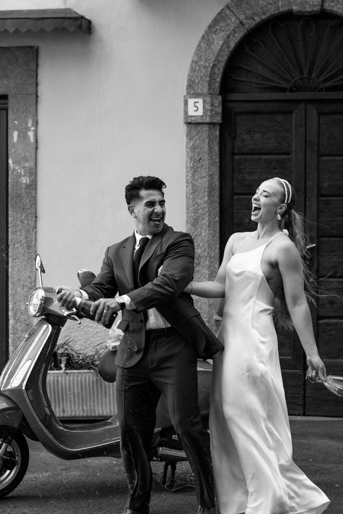 couple toast and cheer in front of vespa elopement 