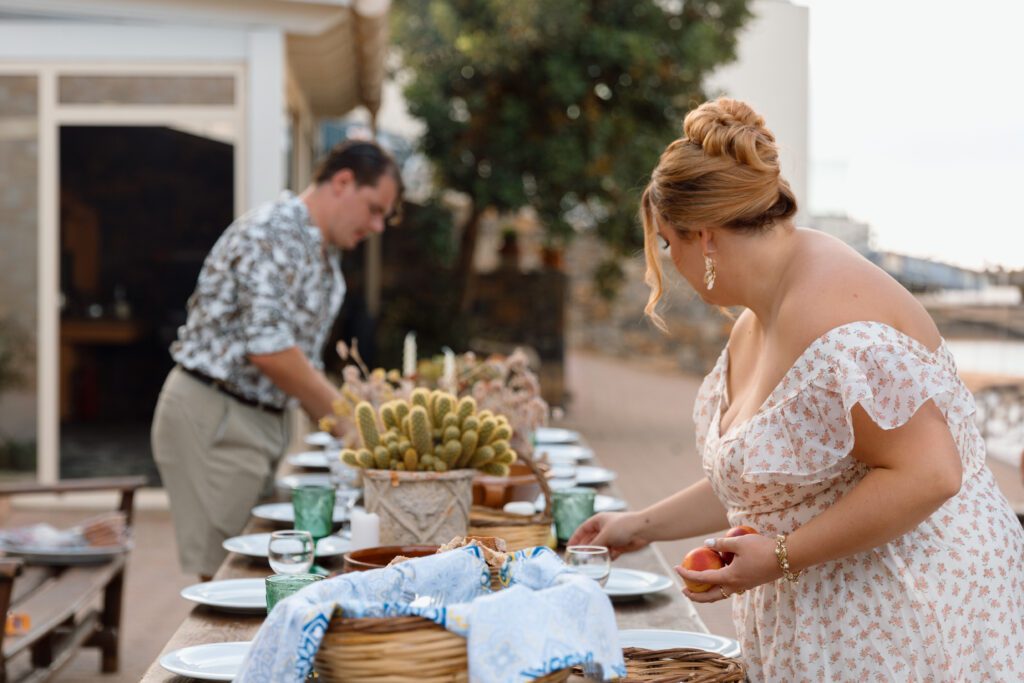 couple prepares for rehearsal dinner setting table on grecian patio elopement