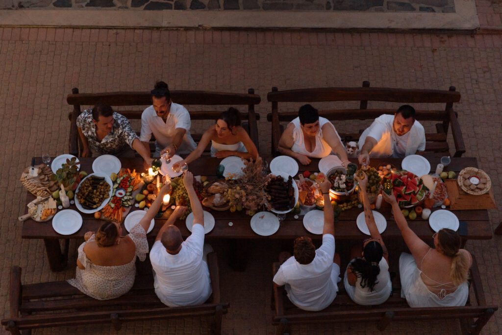 wedding party eats together on patio at twilight in greek elopement