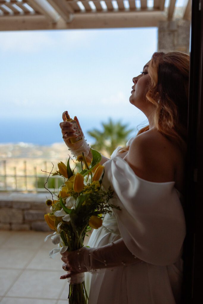 bride sprays perfume with Mediterranean Sea in the background 