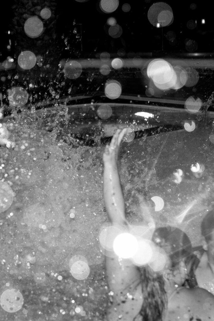 bridal party splashes in the pool at the end of the wedding reception at elopement 